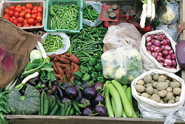 Buy local, eat local. Image of a farmer's market stand filled with vegetables.
