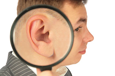 Ringing in the ears. Image of man holding a magnifying glass next to his ear.