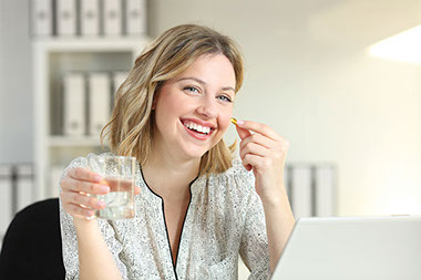 Women holding a glass of water and a vitamin D pill.
