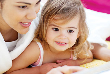 Image of a mom reading a book to her young toddler.