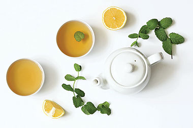 A tea pot with two cups of tea and lemons. A tea pot with two cups of tea and lemons.