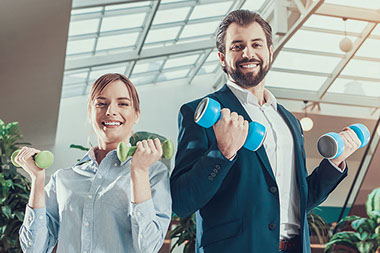 Two coworkers holding a set of dumb bells in hands.