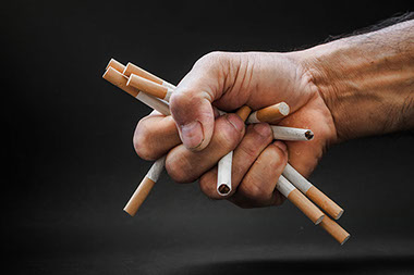 Image of hand crushing a bunch of cigarettes.