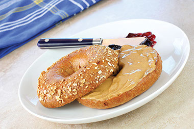 Image of a whole grain bagel with a peanut butter spread.