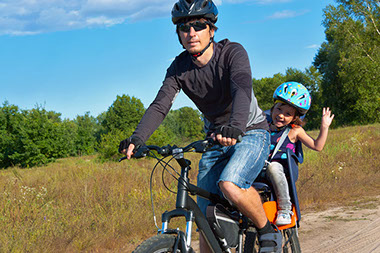 Pedaling safley with your toddler. Image of father and daughter on a bike.