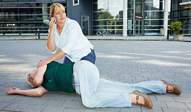 Image of women on phone beside someone who is unresponsive.