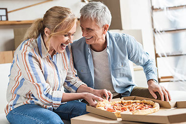 Senior couple eating pizza and laughing.