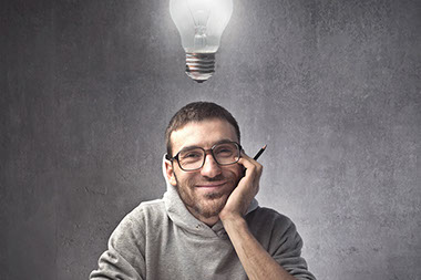 Mind over matter. Image of smiling young man with a light blub above his head.