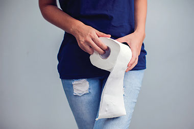 Close up of hands holding toilet paper.