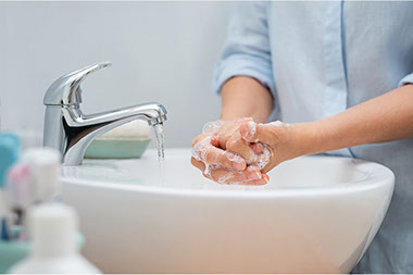 Close up image of person washing hand with soap and water.