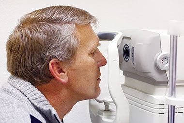 Prevent vision loss. Image of older man getting an eye exam.