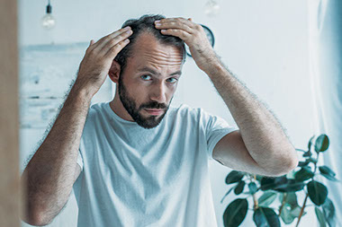 Man looking at hair loss in the mirror. Man looking at hair loss in the mirror.