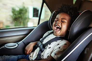 Yound child in a car seat laughing.