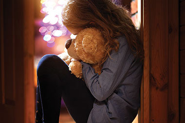 Young child cuddled up with teddy bear.