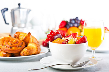 Image of breakfast with fruit and orange juice.