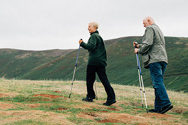 Older couple hiking using walking sticks.