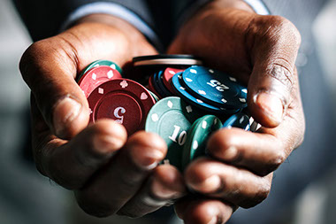 Close up of man's hands holding a bunch of gambling chips.