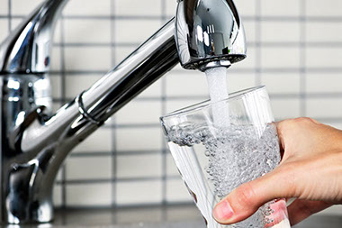 Image of person filling up glass with tap water.