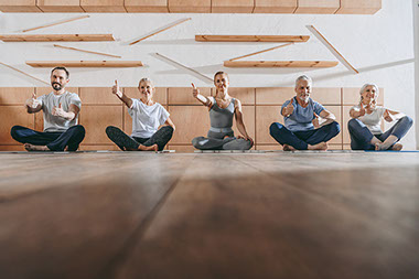 Group of people with thumbs up in yoga studio.