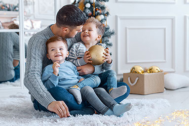 Father and two young boys sitting on his lap.