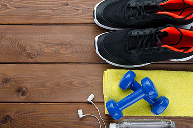 Fitness concept with sneakers dumbbells headphones and bottle of water.