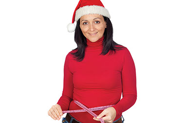 10 ways to avoid holiday weight gain. Image of women wearing a santa hat while taking her waist measurement.