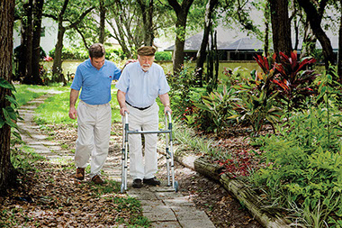 Caregiving takes a toll on marriage. Image of son walking with elderly father.