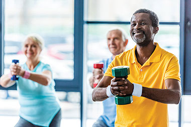Older adults using dumb bells in fitness class.