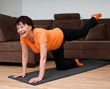 Image of middle-aged women exercising in her living room.