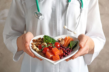 Doctor holding heart shape plate filled with heart healthy foods.