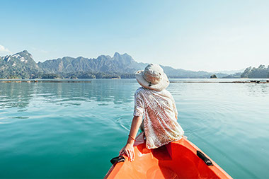 Back of person sitting in canoe on blue lake.