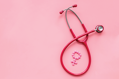 Stethoscope and female symbol pills on pink top view.