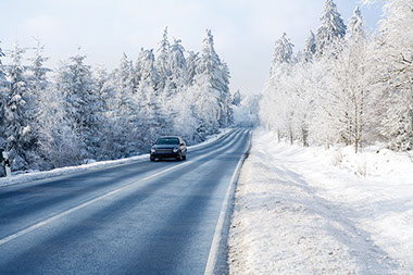 Image of car driving down a snowy road.
