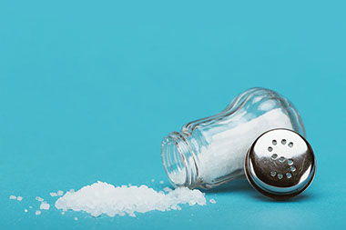 A salt bottle opened with spilled salt.