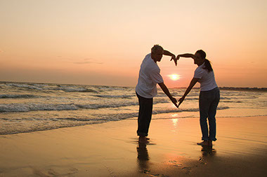Couple on beach making heart shape with their arms. Couple on beach making heart shape with their arms.