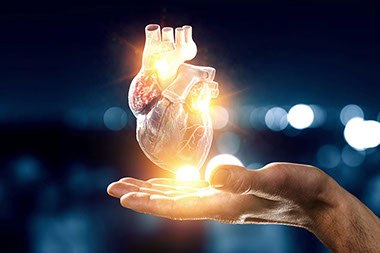 Computer generated heart glowing above hand.