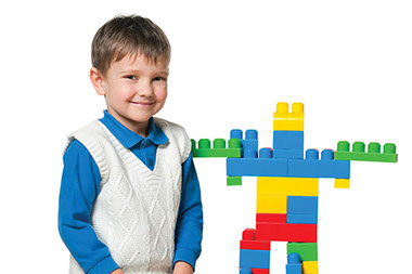 Forget the iPad, let kids play in sand or with blocks. Image of young boy playing with blocks.