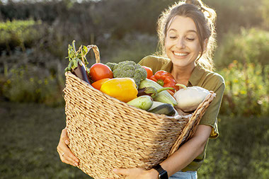Women carrying a basket filled with vegetables. Women carrying a basket filled with vegetables.