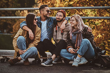 Group of friends sitting outside on skateboards. Group of friends sitting outside on skateboards.