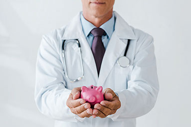 Doctor holding a pink piggy bank in hands.