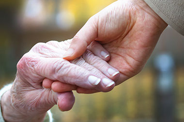 Close up image of two elderly hands holding.