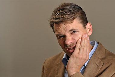 Image of man holding jaw in pain.