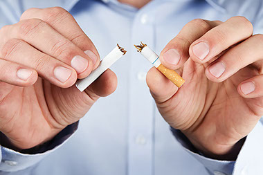 Close-up image of a person breaking a cigarette in half.
