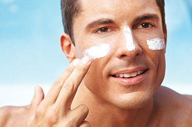 Image of a man placing sunscreen on his face.