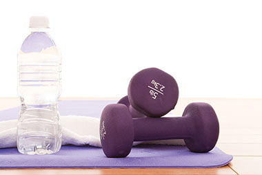 Image of water bottle, towel and dumb bells on a mat.