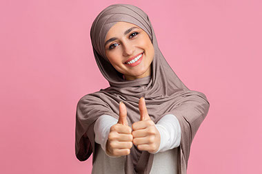 Women smiling with 2 thumbs up.