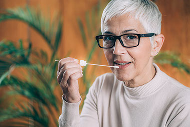 Women holding a swab near her mouth. Women holding a swab near her mouth.