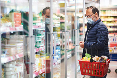 Man at grocery store wearing a face mask covering mouth and nose. Man at grocery store wearing a face mask covering mouth and nose.