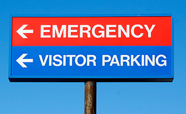 Image of a sign directing where the emergency room is and visitor parking.