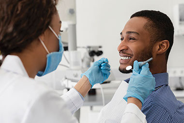 Man smiling at dentist office with dentist about to start exam. Man smiling at dentist office with dentist about to start exam.
